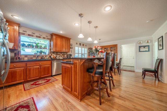 3811 Andes Dr, Redding, CA 96001 - kitchen featuring dishwasher, a sink, a breakfast bar, brown cabinetry, and light wood finished floors
