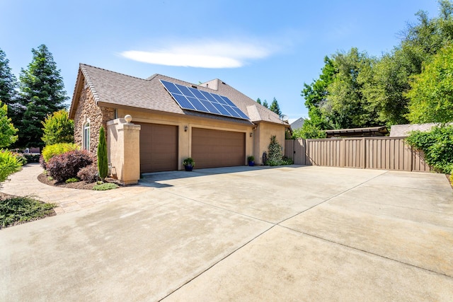 2830 Montana Sky Dr, Redding, CA 96002 - view of side of property featuring an attached garage, roof mounted solar panels, concrete driveway, stucco siding, and stone siding