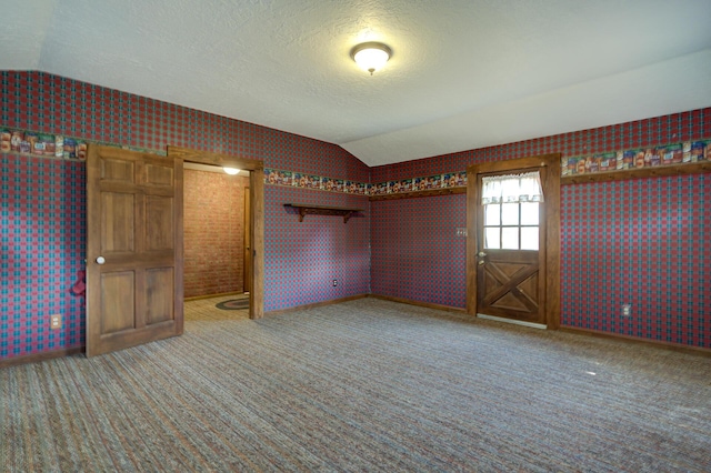 2915 Rockabye Ln, Redding, CA 96002 - unfurnished bedroom featuring lofted ceiling, wallpapered walls, carpet, baseboards, and a textured ceiling