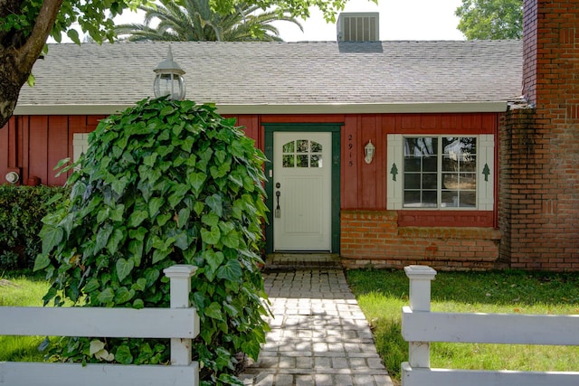 2915 Rockabye Ln, Redding, CA 96002 - view of exterior entry with brick siding, board and batten siding, roof with shingles, a chimney, and cooling unit