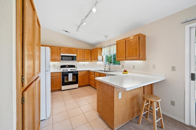 1626 French Lace Ln, Redding, CA 96003 - kitchen featuring range with gas stovetop, stainless steel microwave, a sink, freestanding refrigerator, and a peninsula