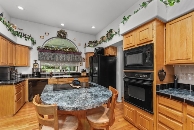 15947 Butterfield Ln, Anderson, CA 96007 - kitchen with black appliances, a breakfast bar area, light wood-style flooring, backsplash, and a sink