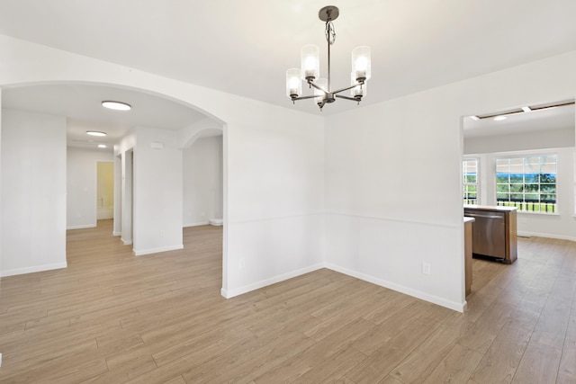 13360 Oak Run Rd, Oak Run, CA 96069 - spare room featuring light wood-type flooring, arched walkways, a chandelier, and baseboards