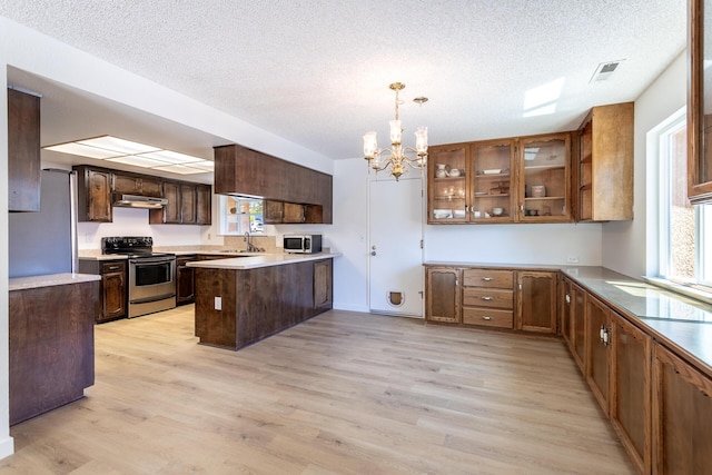 3640 Oro St, Redding, CA 96001 - kitchen with stainless steel appliances, a sink, a chandelier, light wood-style floors, and a textured ceiling
