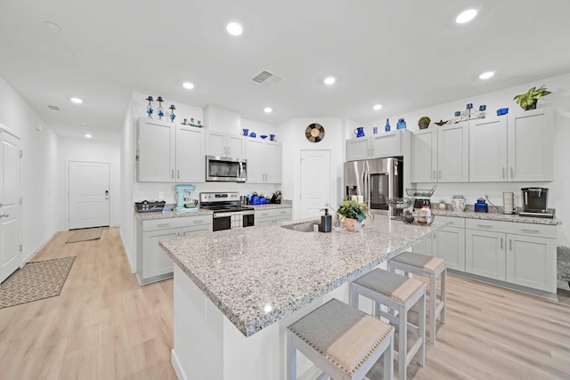 2764 Austere Ave, Redding, CA 96003 - kitchen featuring appliances with stainless steel finishes, a breakfast bar, light wood-style floors, a center island with sink, and recessed lighting