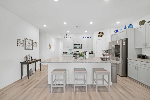 2764 Austere Ave, Redding, CA 96003 - kitchen with stainless steel appliances, light wood-style flooring, a breakfast bar, a kitchen island with sink, and recessed lighting