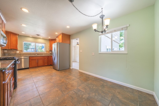5101 Bidwell Rd, Redding, CA 96001 - kitchen featuring appliances with stainless steel finishes, brown cabinetry, backsplash, a chandelier, and baseboards