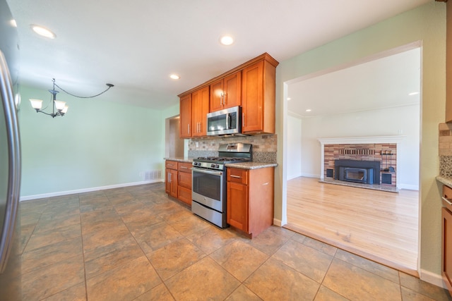 5101 Bidwell Rd, Redding, CA 96001 - kitchen featuring appliances with stainless steel finishes, brown cabinets, a chandelier, light stone counters, and recessed lighting