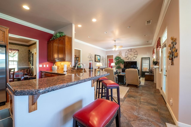 24943 Cox Ln, Los Molinos, CA 96055 - kitchen featuring a breakfast bar area, baseboards, a peninsula, a ceiling fan, and ornamental molding