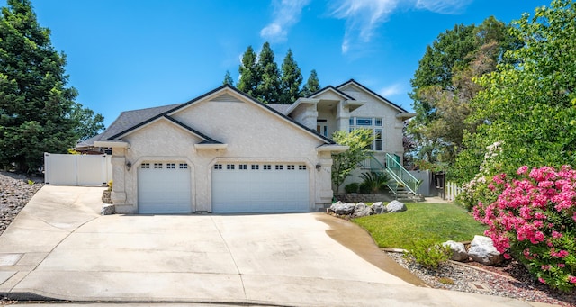 1030 Tulare Ct, Redding, CA 96003 - view of front facade with a garage, driveway, a front lawn, stairway, and stucco siding