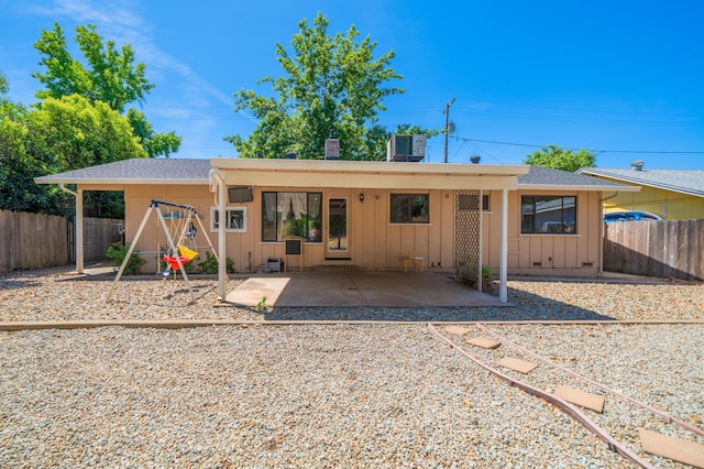 2006 Vale Dr, Redding, CA 96002 - rear view of property with board and batten siding, a fenced backyard, a patio, a playground, and central air condition unit