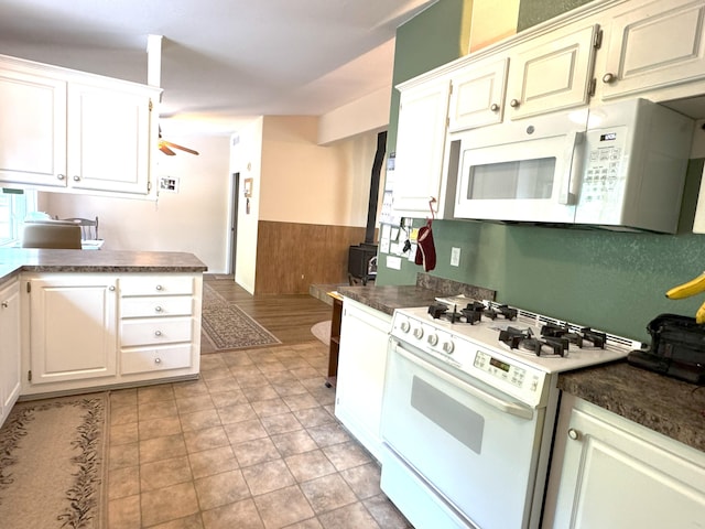 29093 Day Rd, Mcarthur, CA 96056 - kitchen with white appliances, dark countertops, ceiling fan, wainscoting, and white cabinets
