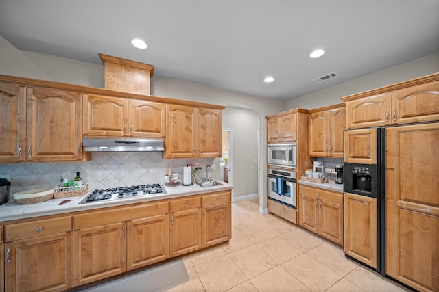 3921 Silver Lace Ln, Redding, CA 96001 - kitchen with built in appliances, under cabinet range hood, arched walkways, backsplash, and light tile patterned floors