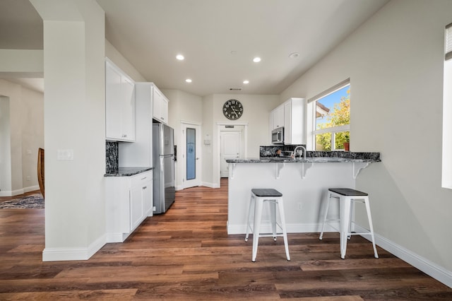 1005 Albion Ave, Redding, CA 96003 - kitchen with stainless steel appliances, recessed lighting, dark stone countertops, a kitchen bar, and white cabinets