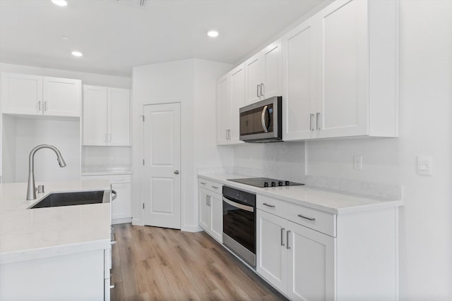 4206 Acadia Pl, Redding, CA 96001 - kitchen with appliances with stainless steel finishes, a sink, white cabinets, light wood finished floors, and recessed lighting