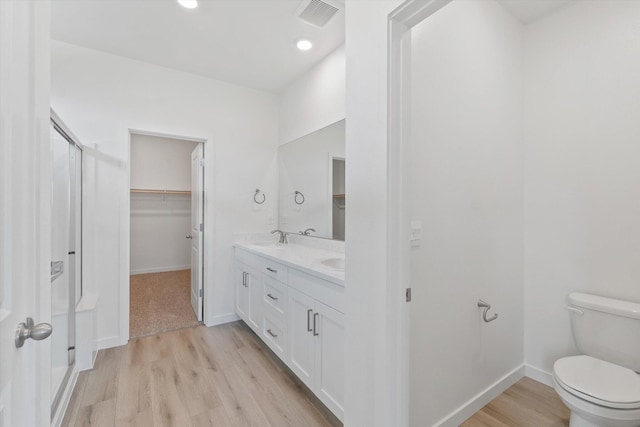 4206 Acadia Pl, Redding, CA 96001 - bathroom featuring wood finished floors, double vanity, a stall shower, toilet, and a spacious closet
