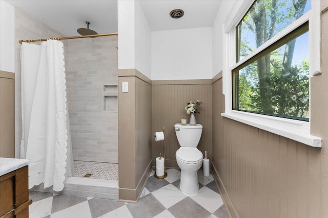 2551 S Waverly Ave, Redding, CA 96001 - full bathroom featuring wainscoting, a tile shower, vanity, and toilet