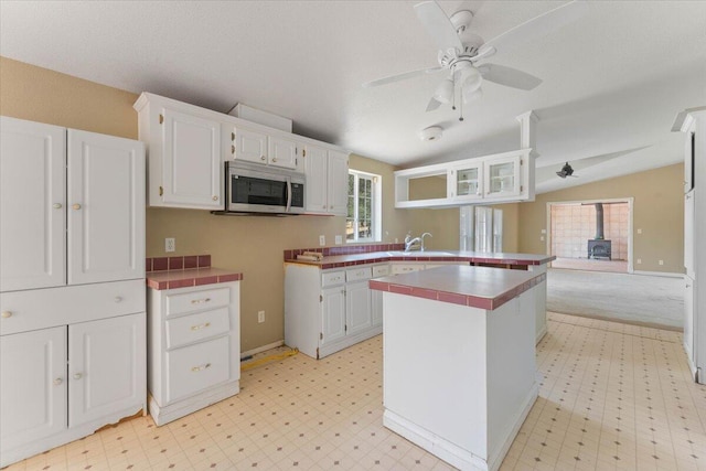 22400 E Elk Trl, Redding, CA 96003 - kitchen with stainless steel microwave, a wood stove, a sink, lofted ceiling, and light flooring