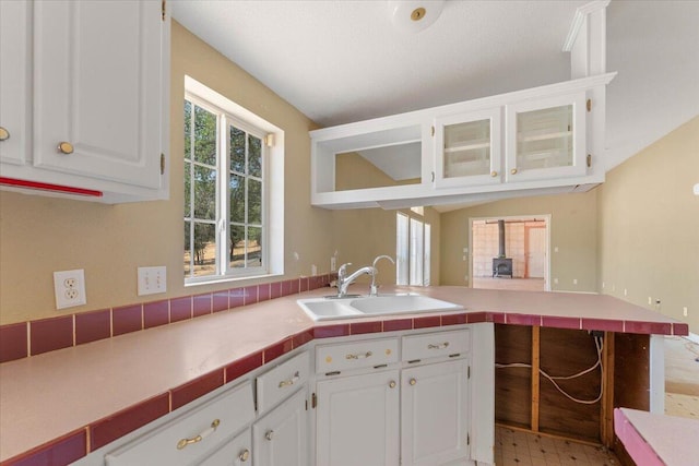 22400 E Elk Trl, Redding, CA 96003 - kitchen featuring a sink, a peninsula, white cabinets, glass insert cabinets, and light flooring