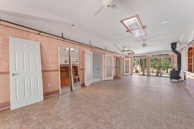 22400 E Elk Trl, Redding, CA 96003 - unfurnished room with a ceiling fan, a wood stove, a wainscoted wall, vaulted ceiling, and french doors