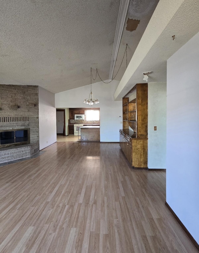 846 Ridge Rd, Redding, CA 96003 - unfurnished living room featuring a fireplace, a textured ceiling, wood finished floors, a chandelier, and vaulted ceiling