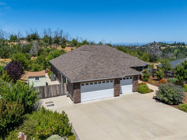4648 Kilkee Dr, Redding, CA 96001 - view of front facade with concrete driveway, stone siding, a garage, and a shingled roof