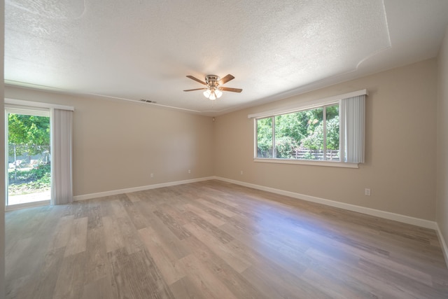 5867 Bell Rd, Redding, CA 96001 - empty room featuring healthy amount of natural light, a textured ceiling, ceiling fan, light wood-style flooring, and baseboards