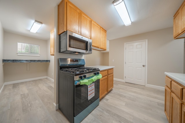5867 Bell Rd, Redding, CA 96001 - kitchen with appliances with stainless steel finishes, light wood finished floors, light countertops, and baseboards