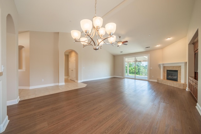 3337 Old Lantern Dr, Redding, CA 96003 - unfurnished living room with wood finished floors, a tiled fireplace, arched walkways, a chandelier, and high vaulted ceiling