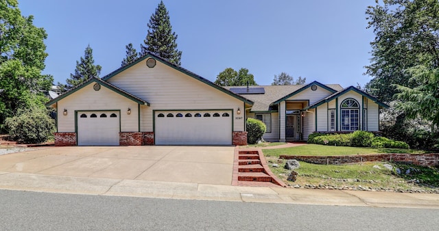 3097 Butterfly Ln, Shasta Lake, CA 96019 - ranch-style house featuring an attached garage, roof mounted solar panels, concrete driveway, brick siding, and a front yard