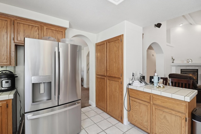 3097 Butterfly Ln, Shasta Lake, CA 96019 - kitchen featuring stainless steel fridge, arched walkways, a peninsula, light tile patterned flooring, and tile countertops