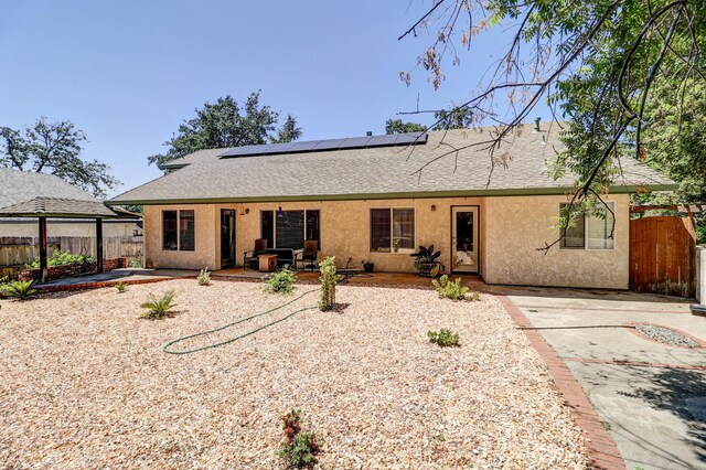 3097 Butterfly Ln, Shasta Lake, CA 96019 - back of property with stucco siding, a shingled roof, solar panels, and a patio
