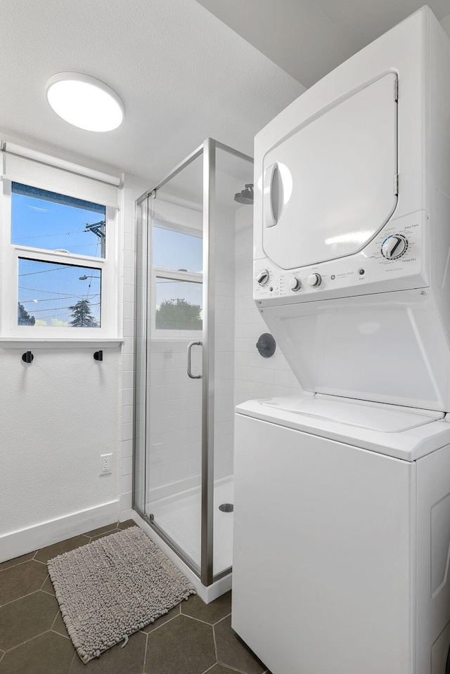 2180 Oak Ridge Dr, Redding, CA 96001 - washroom featuring stacked washer / dryer, dark tile patterned flooring, and a textured ceiling
