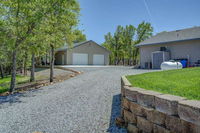 17400 Pittim Dr, Redding, CA 96003 - view of property exterior with gravel driveway, a garage, stucco siding, and central AC