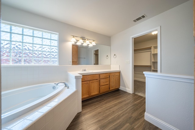 3255 Wandsworth Dr, Shasta Lake, CA 96019 - bathroom with a garden tub, vanity, wood finished floors, a spacious closet, and a chandelier