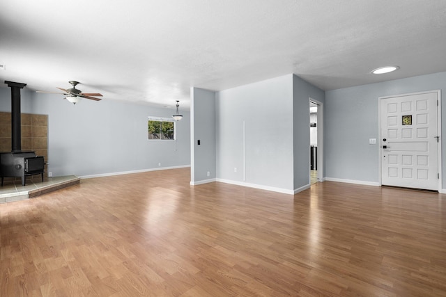 1401 Casa Vereda Way, Redding, CA 96003 - unfurnished living room featuring a wood stove, a ceiling fan, and wood finished floors