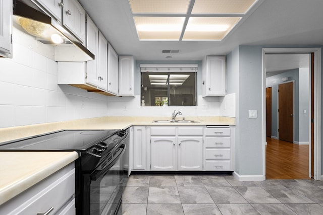 1401 Casa Vereda Way, Redding, CA 96003 - kitchen with black range with electric stovetop, white cabinets, under cabinet range hood, and light countertops