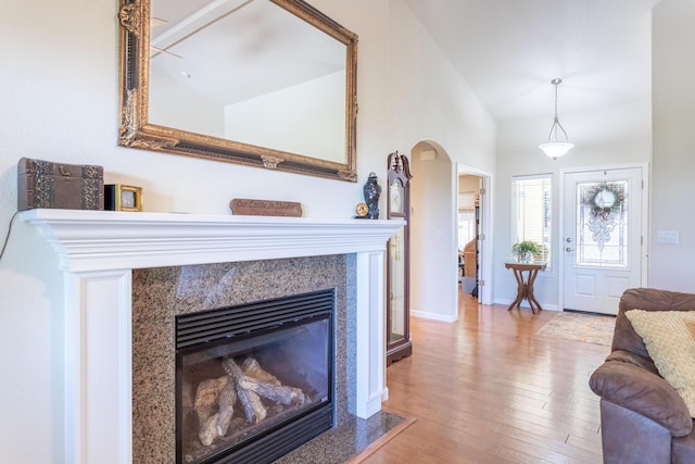 7256 Shasta Forest Dr, Shingletown, CA 96088 - living area featuring wood finished floors, baseboards, a high end fireplace, lofted ceiling, and arched walkways