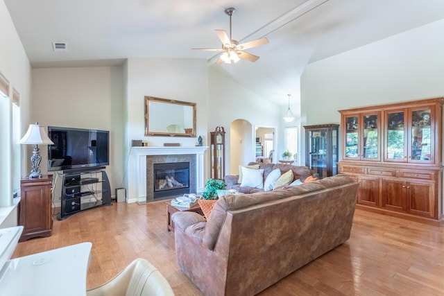 7256 Shasta Forest Dr, Shingletown, CA 96088 - living room featuring arched walkways, a ceiling fan, light wood-style floors, high vaulted ceiling, and a fireplace