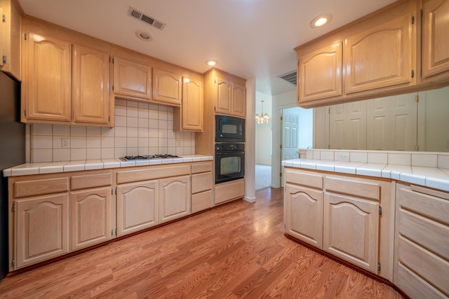 2169 Hope Ln, Redding, CA 96003 - kitchen with black appliances, light brown cabinetry, light wood-style floors, backsplash, and recessed lighting