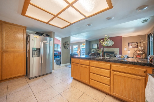 1136 Woodland Ter, Redding, CA 96002 - kitchen featuring stainless steel refrigerator with ice dispenser, tile countertops, light tile patterned floors, a fireplace, and a peninsula