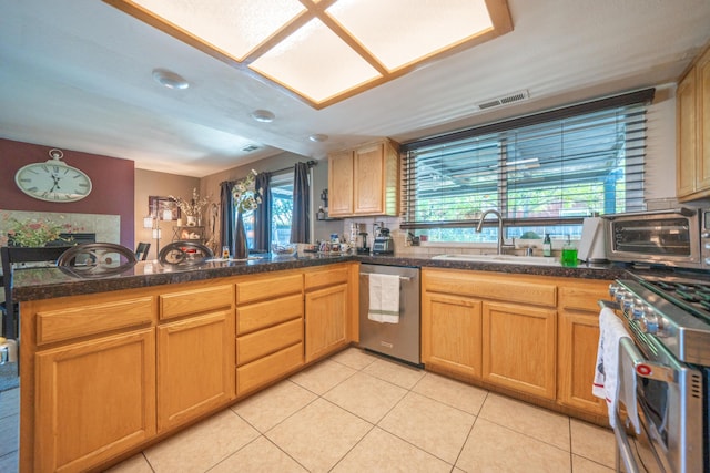 1136 Woodland Ter, Redding, CA 96002 - kitchen with stainless steel appliances, a sink, light tile patterned flooring, a peninsula, and dark countertops