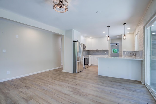 3090 Inez St, Redding, CA 96002 - kitchen with appliances with stainless steel finishes, light countertops, decorative backsplash, light wood-style flooring, and white cabinetry
