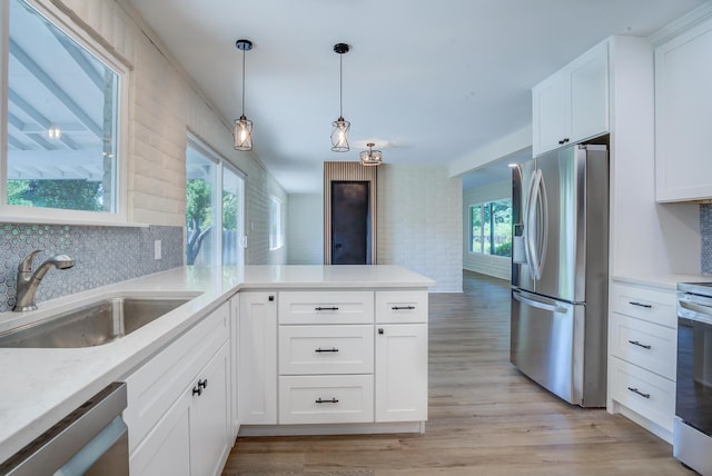 3090 Inez St, Redding, CA 96002 - kitchen featuring appliances with stainless steel finishes, a sink, white cabinetry, tasteful backsplash, and a peninsula
