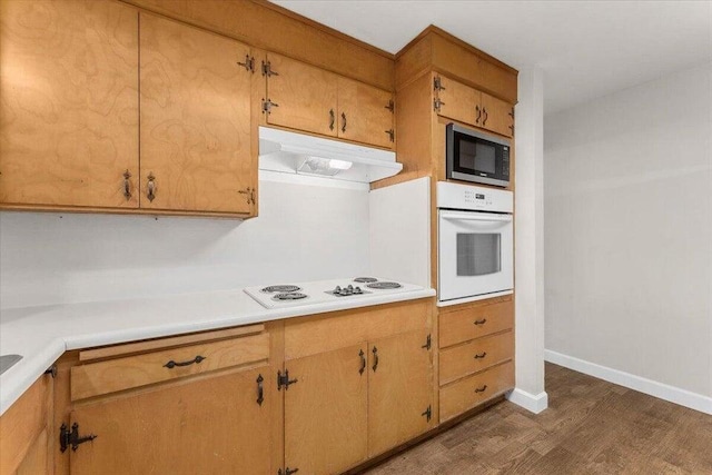 4200 Travona St, Redding, CA 96001 - kitchen featuring white appliances, under cabinet range hood, dark wood-style floors, light countertops, and baseboards