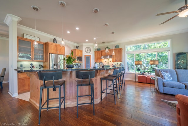 3179 Pinot Path, Redding, CA 96001 - kitchen featuring stainless steel refrigerator with ice dispenser, a kitchen breakfast bar, under cabinet range hood, tasteful backsplash, and crown molding