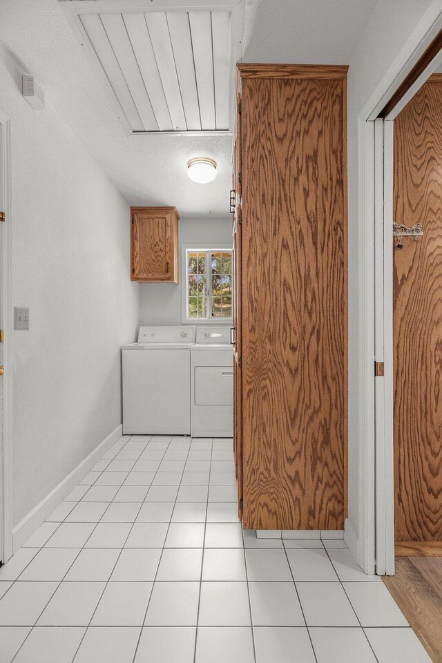 21247 Creekside Dr, Red Bluff, CA 96080 - laundry area featuring separate washer and dryer, cabinet space, light tile patterned flooring, and baseboards