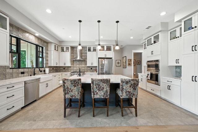 180 Agua Verdi Dr, Red Bluff, CA 96080 - kitchen with stainless steel appliances, wall chimney exhaust hood, decorative backsplash, a center island with sink, and recessed lighting