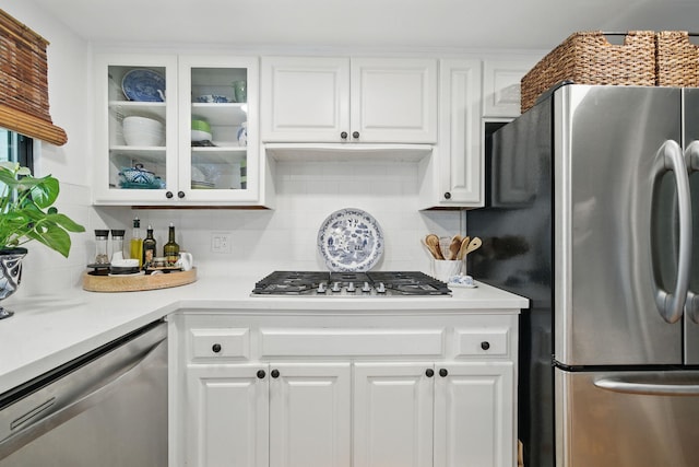 6966 Granada Dr, Redding, CA 96002 - kitchen featuring appliances with stainless steel finishes, white cabinets, backsplash, light countertops, and glass insert cabinets