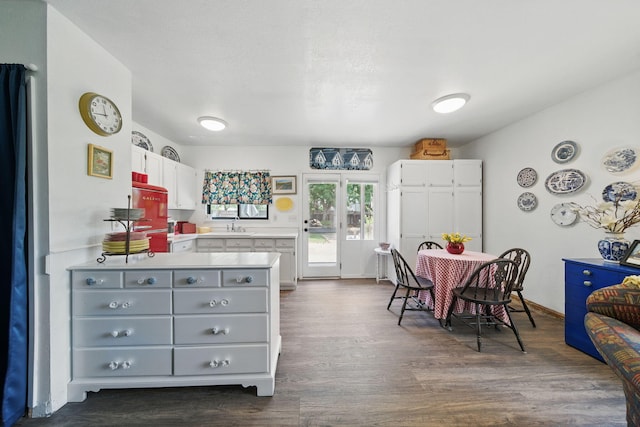 6966 Granada Dr, Redding, CA 96002 - kitchen with white cabinets, dark wood-style flooring, light countertops, a peninsula, and a sink